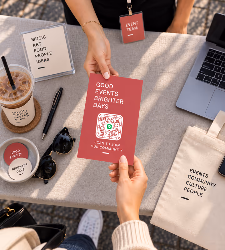 A red “Scan to join our community” flyer with a square QR code, handed across a table by a member of the event team