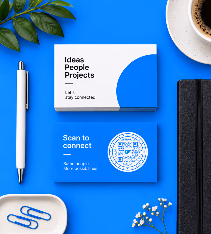 Blue business cards, the top one reading “Scan to connect” with a circular QR code, on a blue desk beside a pen and a cup of coffee
