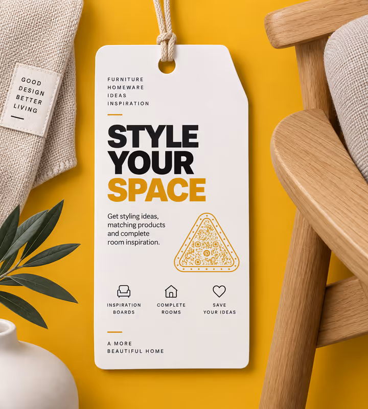 A white “Style your space” swing tag with a yellow triangular QR code, on a yellow background beside an oak chair and a linen cushion