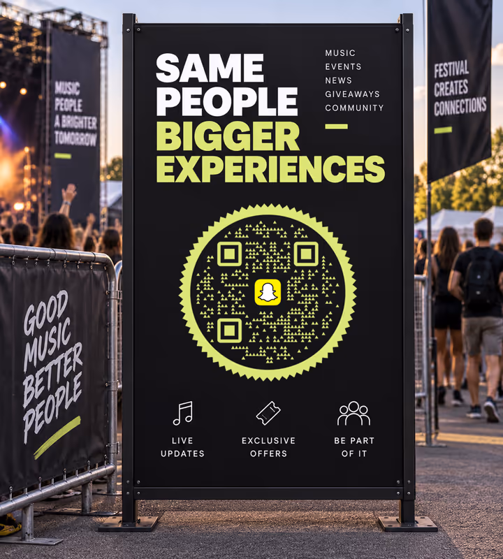 A black festival sign reading “Same people, bigger experiences” with a yellow-green circular QR code, the crowd and stage behind it