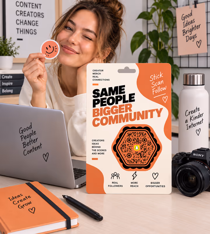 An orange sticker sheet reading “Same people, bigger community” with a hexagonal QR code, held up by a creator at a desk with a camera and laptop