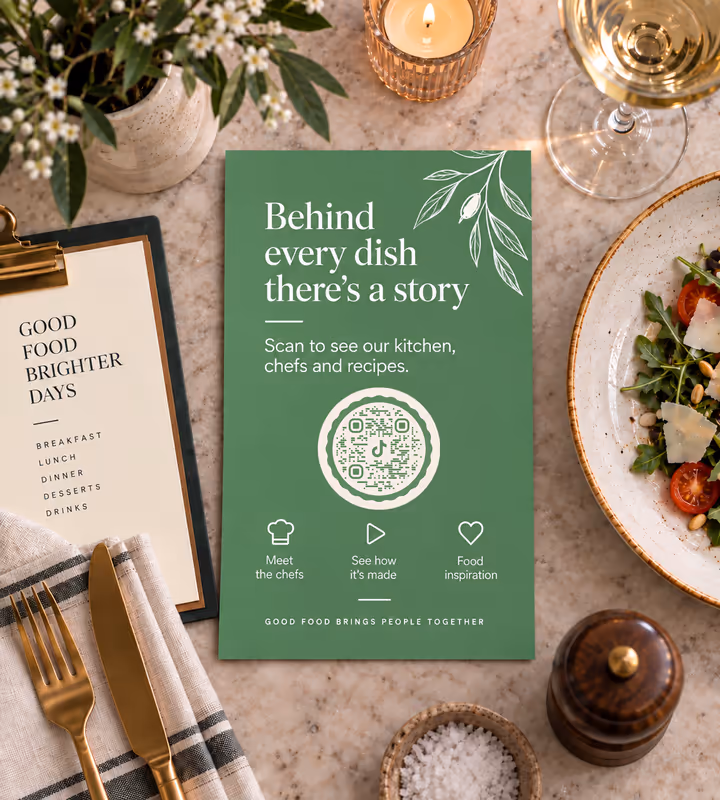 A green restaurant table card reading “Behind every dish there's a story” with a white circular QR code, beside a plated salad and cutlery