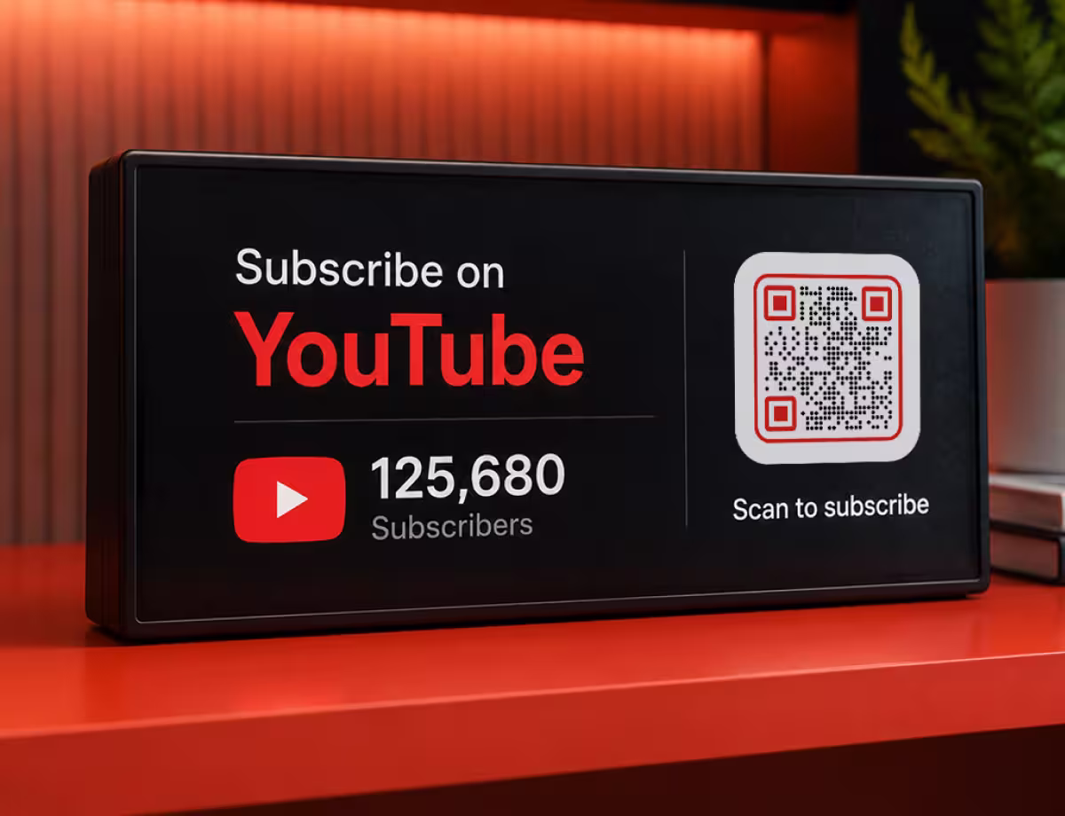 A screen reading “Subscribe on YouTube - scan to subscribe” with a QR code and subscriber count, on an orange shelf