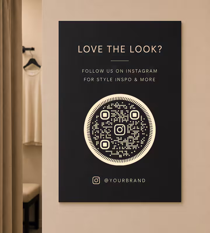 A black “Love the look?” poster with a gold circular QR code, mounted on a fitting-room wall