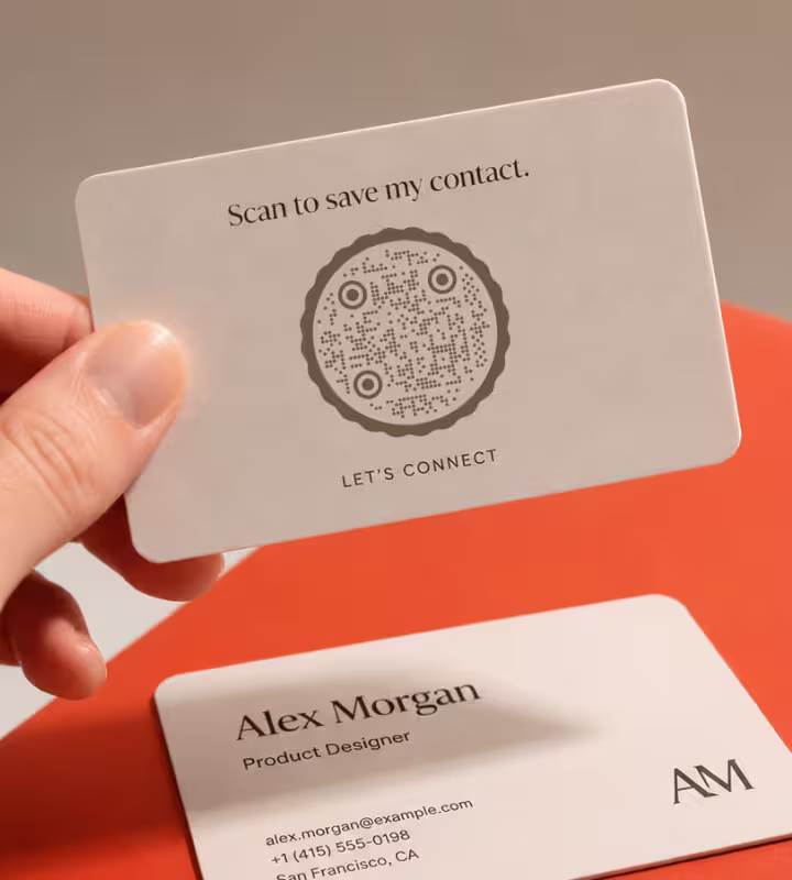 A hand holding a business card that reads “Scan to save my contact” with a QR code