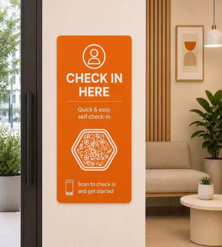 Uma placa laranja de autoatendimento ao lado da porta de entrada com «Faça o check-in aqui: rápido e simples», um QR code hexagonal e a sala de espera ao fundo