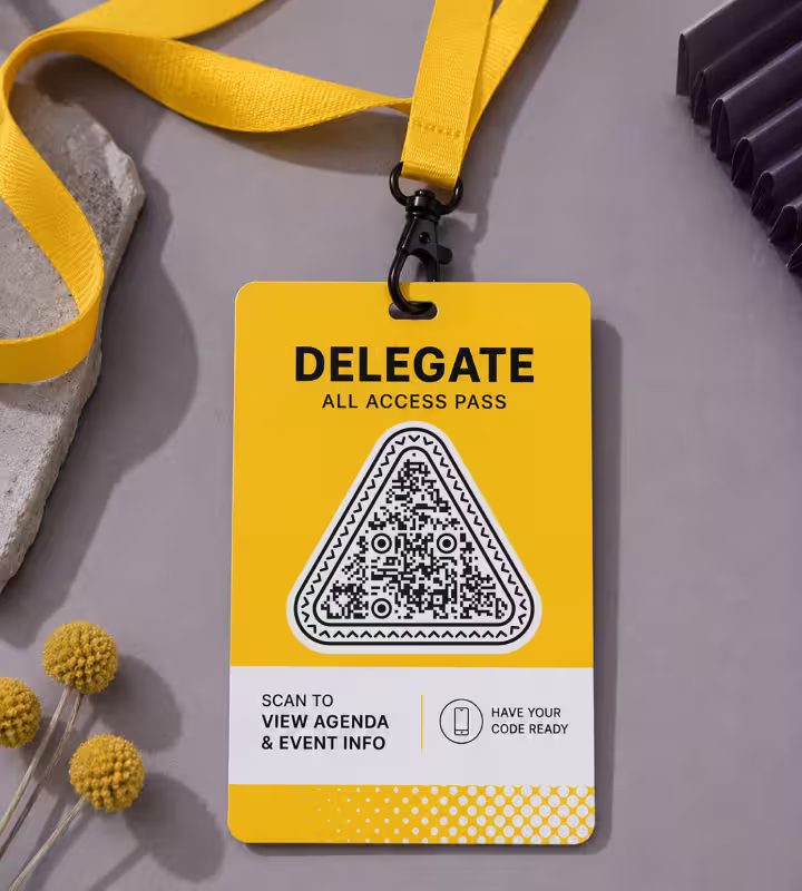 A yellow delegate badge on a lanyard reading “Delegate - all access pass”, with a triangular QR code and “Scan to view agenda & event info”