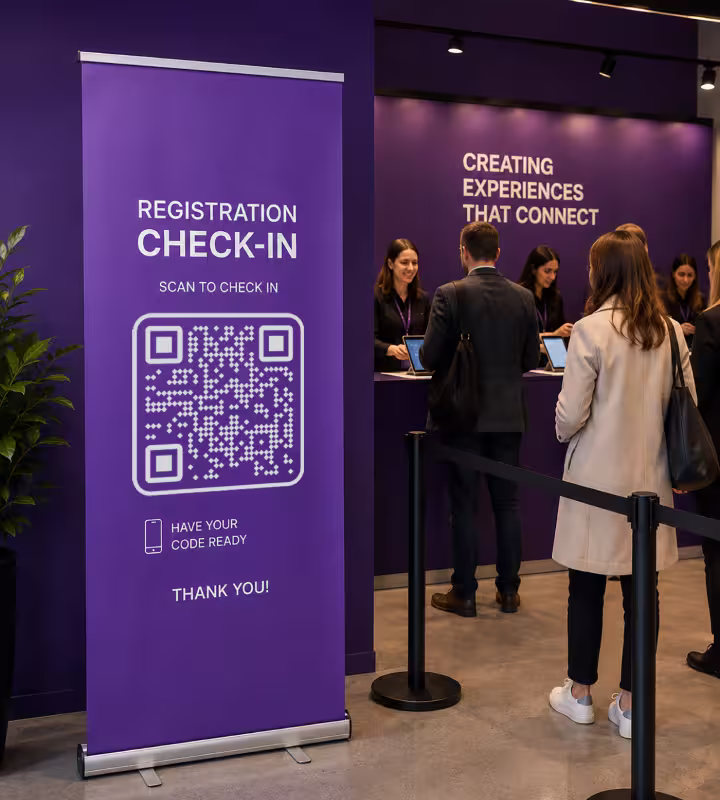 A purple pull-up banner beside the registration desk reading “Registration check-in - scan to check in”, with a large QR code and a queue of delegates behind it