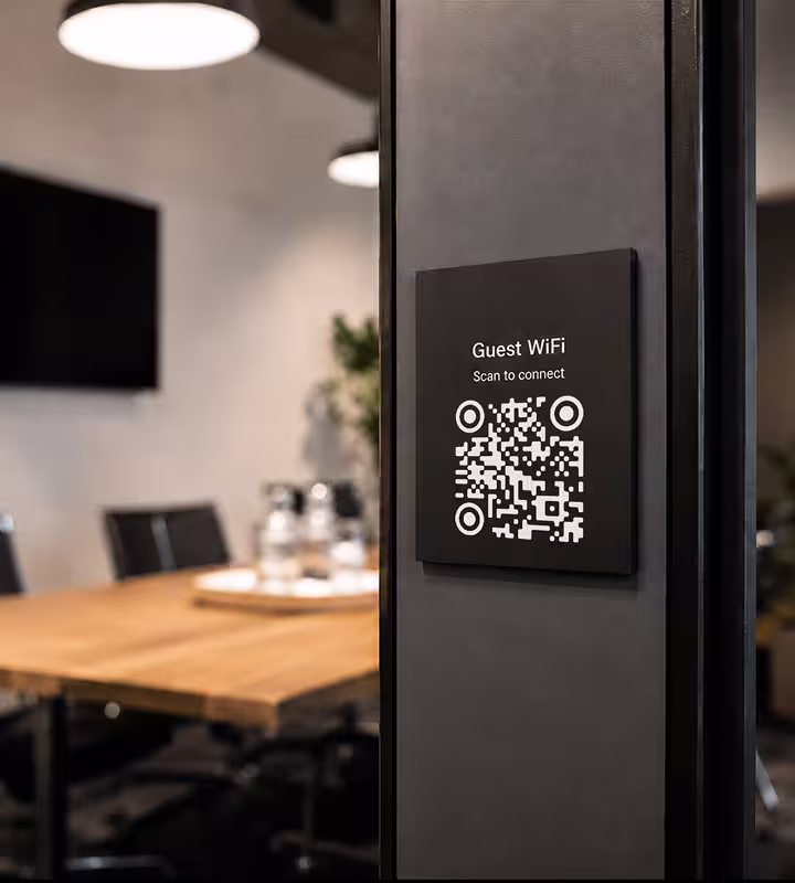 A dark “Guest WiFi - scan to connect” plaque mounted beside the door of a hotel meeting room